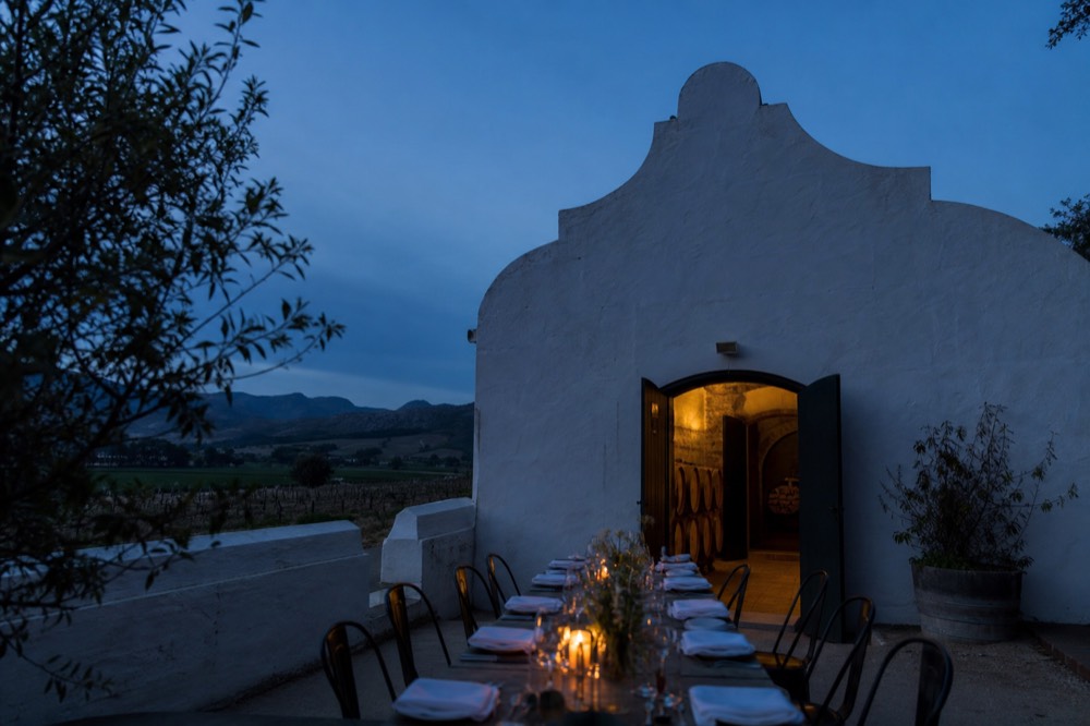Long table set for lunch overlooking vineyards and hills, no text, no logos, no people