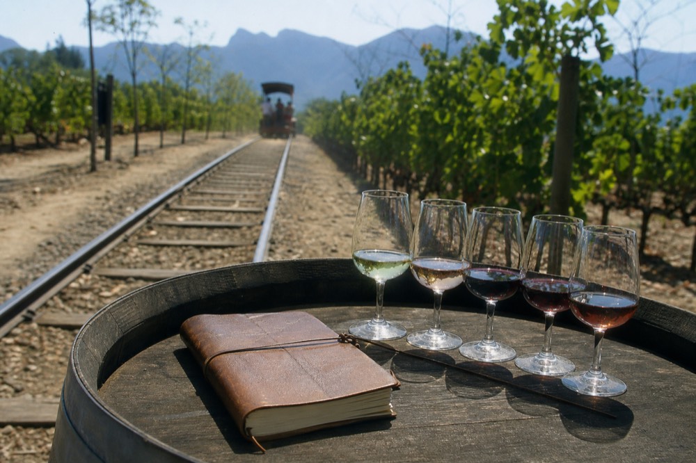 A traveler's notebook and a tasting flight on a wooden barrel top, no text, no logos, no people