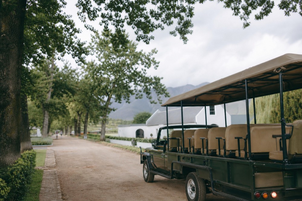 Open-air tram-bus parked at a Franschhoek wine estate stop, no text, no logos, no people