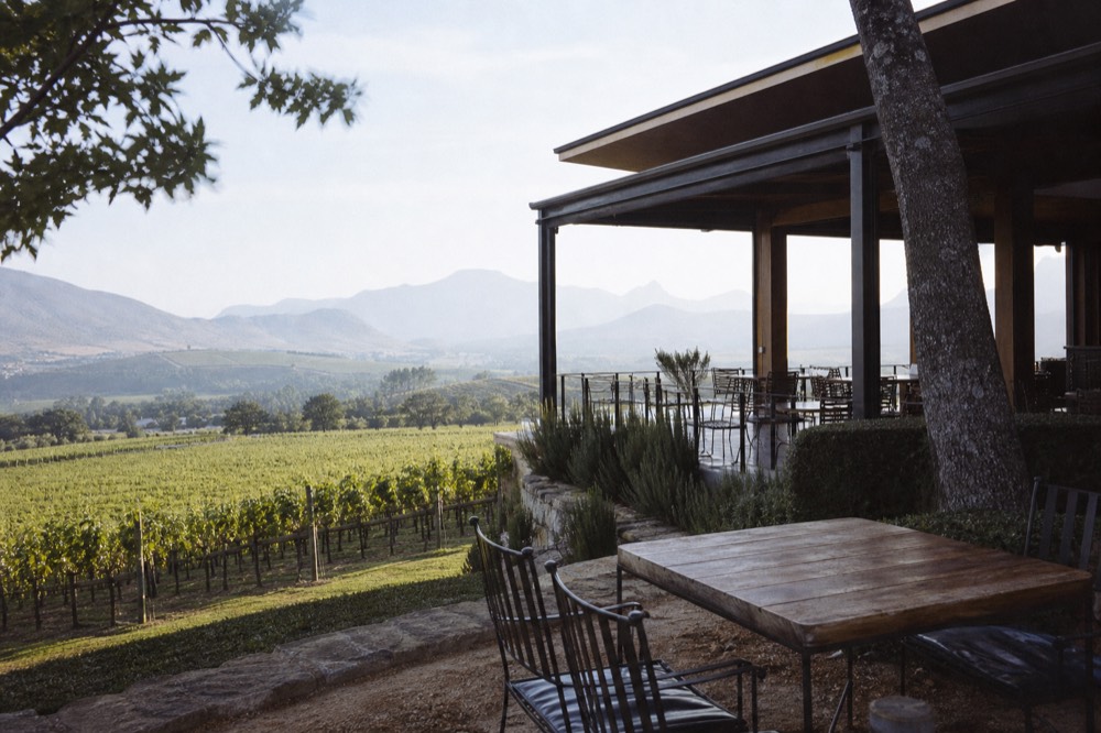 A quiet Paarl tasting room terrace with empty chairs overlooking vines, no text, no logos, no people